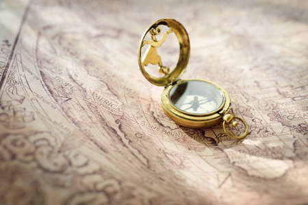 Retro styled golden compass (sundial) and old white nautical chart. Vintage still life. Sailing...