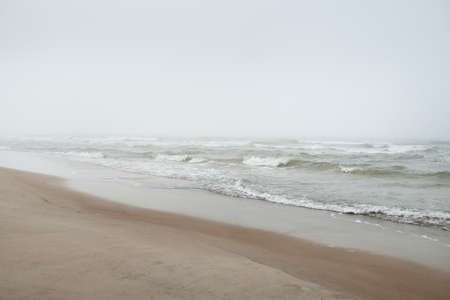 Baltic sea in a thick white fog. Waves, splashing water, storm. Natural textures. Picturesque panoramic monochrome scenery, seascape. Nature, environment, rough weather, shipwreck, dangerの写真素材