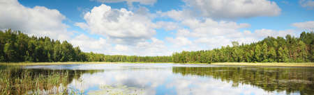 Blue lake, green birch tree forest, Estonia. Picturesque panoramic scenery. Reflections in the water. Atmospheric landscape. Pure nature, ecology, environmental conservation, travel destinationsの写真素材