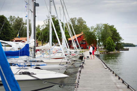 Classic and modern sloop rigged sailboats moored to a wooden pier (jetty). Summer vacations, recreation, sport, regatta, leisure activity. service, private vessel. BjÃ¶rkÃ¶ island, lake MÃ¤laren, Swedenの写真素材