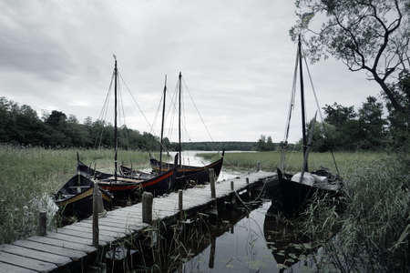 Wooden sailing boats moored to a pier. Birka, BjÃ¶rkÃ¶ island, lake MÃ¤laren, Sweden....