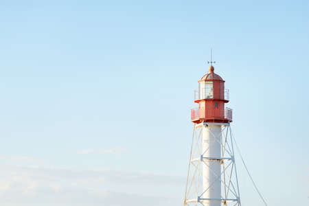 Lighthouse against clear blue sunset sky. Soft light, golden hour. Pape village, Latvia. Idyllic landscape. Construction, coast guard, navigation, symbol of hope and peace. Panoramic view, copy spaceの写真素材