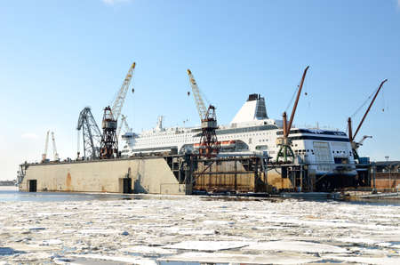 white passenger ferry is being fixed at the shipyard dock in the port of Riga