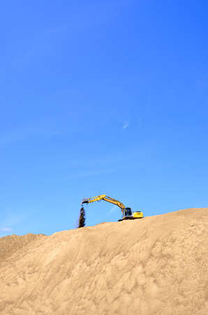 new yellow excavator working on sand dunesの写真素材