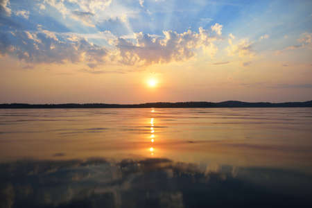 Sunset at a forest lake. Calm lake surface view.の写真素材