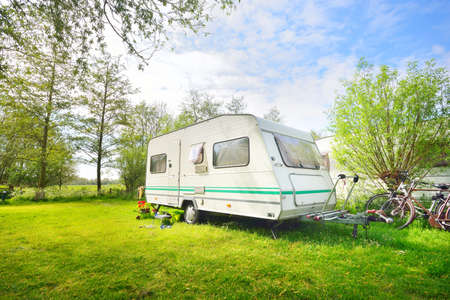 Caravan trailer camping on a green lawn under a tree in springtime