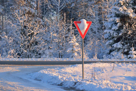Snowcovered give way warning sign on a highway crossing