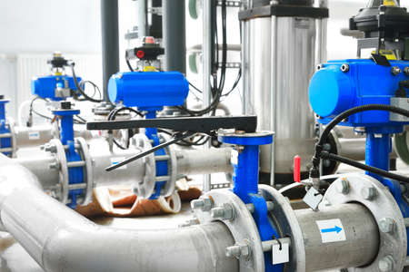 Large industrial water treatment and boiler room. Shiny steel metal pipes and blue pumps and valves.の写真素材