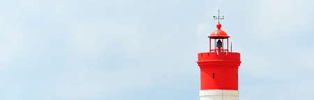 A Christmas lighthouse (Dique De La Navidad) against cloudy blue sky, close-up. Mediterranean sea, Cartagena, Spain. Navigation, sailing, cruise, traveling, national landmark, symbol of hope and peaceの写真素材