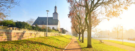 An empty alley through the park near Rhine river, church in the background. No people because of...