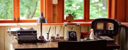 Interior of the cabinet of the old train station in Riga, Latvia. Wooden furniture, vintage clock, telephone and antique typewriter close-up. Concept image, past, history, museum, educationの写真素材
