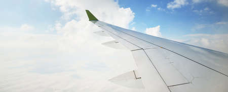 Clear blue sky with fluffy ornamental cumulus clouds, panoramic view from an airplane, wing close-up. Dreamlike cloudscape. Travel, tourism, vacations, weekend, freedom, peace, hope, heaven conceptsの写真素材