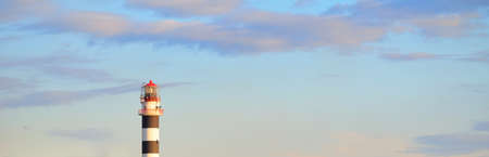 An old lighthouse, range marker and breakwaters at sunset. Baltic sea, Riga, Latvia. Idyllic landscape. A view from the sailboat. Transportation, sailing, navigation. Symbol of hope and peaceの写真素材