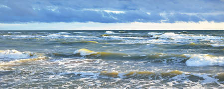 Baltic sea after a thunderstorm at sunset. Ventspils, Latvia. Colorful glowing clouds. Waves and...
