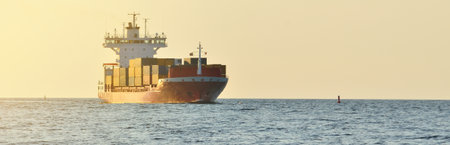 Large cargo container ship leaving the port of Norfolk at sunset, close-up. Virginia, USA. Freight...