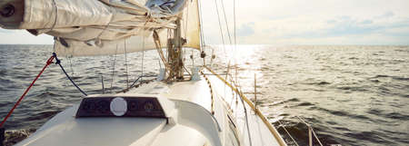 White yacht sailing in an open sea on a sunny summer day. Top down view from the deck to the bow and...