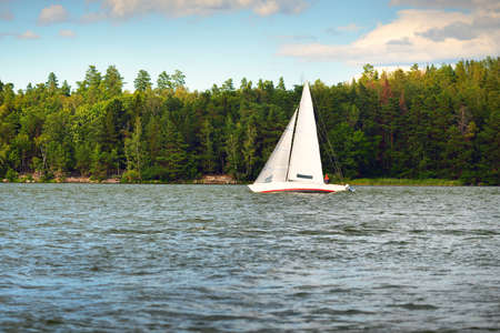 White sloop rigged yacht sailing on a clear day. Slandon, MÃ¤laren lake, Sweden. Summer vacations, transportation, tourism, cruise, recreation, sport, leisure activity, racing, regatta, lifestyleの写真素材