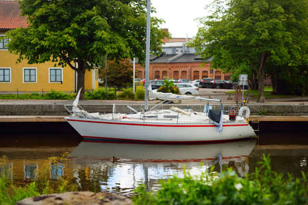 32 feet swedish built cruising sailboat anchored in canal. Green summer park. EnkÃ¶ping, lake MÃ¤laren, Sweden. Vacations, travel destinations, tourism, sailing, cruise, recreation, transportationの写真素材