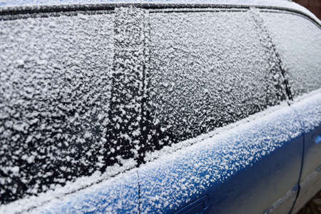 Snowflakes on a car window after a blizzard, close-up. Cold weather, winter, climate change, cleaning and care, dangerous driving conceptsの写真素材