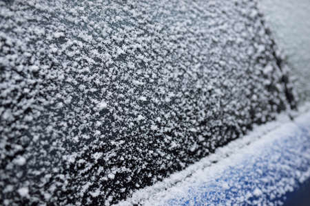 Snowflakes on a car window after a blizzard, close-up. Cold weather, winter, climate change, cleaning and care, dangerous driving conceptsの写真素材