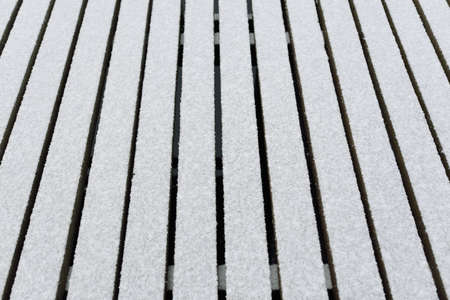 Snow-covered modern wooden pier (jetty, boardwalk) over the frozen river. Ice, frost, snow textures. Decoration, design, graphic resources, copy space, winter backgroundの写真素材