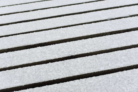 Snow-covered modern wooden pier (jetty, boardwalk) over the frozen river. Ice, frost, snow textures....