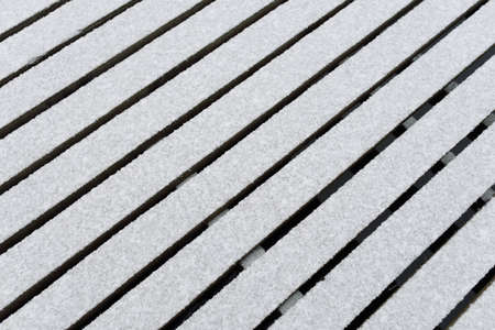Snow-covered modern wooden pier (jetty, boardwalk) over the frozen river. Ice, frost, snow textures. Decoration, design, graphic resources, copy space, winter backgroundの写真素材