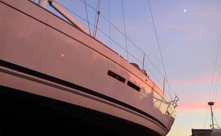 Elegant and modern sailboats standing on land in a yacht club (marina) at sunset. Sailing, cruise,...