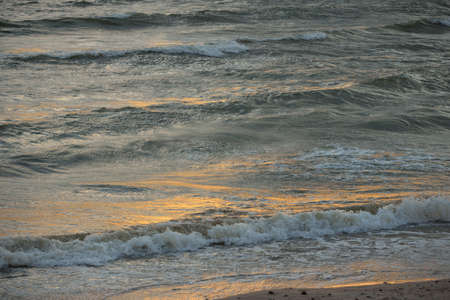 Baltic sea shore after the storm. Sunset, soft golden sunlight. Water surface texture, crashing...