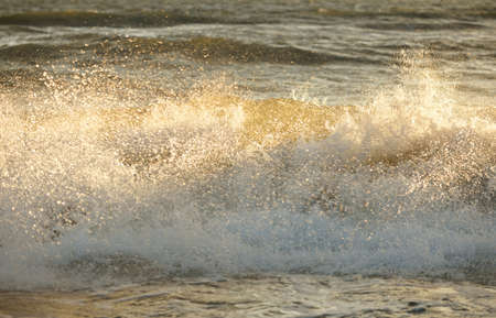 Baltic sea shore after the storm. Sunset, soft golden sunlight. Water surface texture, crashing...
