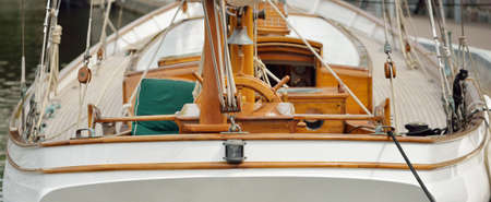 Expensive retro sailing boat (ketch) moored to a pier in a new yacht marina. Wooden teak deck,...