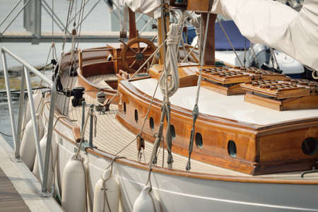 Expensive retro sailing boat (ketch) moored to a pier in a new yacht marina. Wooden teak deck,...