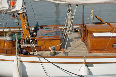 Expensive retro sailing boat (ketch) moored to a pier in a new yacht marina. Wooden teak deck,...