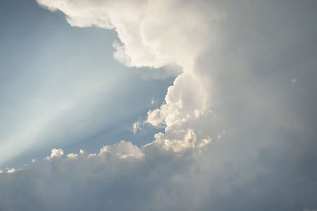 Epic storm cloudscape. White ornamental sunset cumulus clouds. Soft golden sunlight. Clear blue sky....
