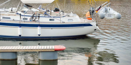 White cruising sailboat moored to a pier in a new yacht marina. Nautical vessel, transportation,...