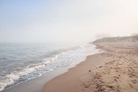 Panoramic view of the Baltic sea shore in a fog at sunrise. Beach, sand dunes. Soft sunlight. Idyllic summer seascape. Nature, environment, vacations, ecotourism, walking and exploring conceptsの写真素材