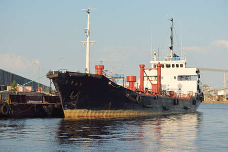 Tanker ship loading in port terminal. Baltic sea. Freight transportation, logistics, global communications, economy, business, industry, fuel and power generation, supplyの写真素材