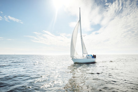 White sloop rigged yacht sailing in an open sea. Clear sky, cloudscape. A view from the sailboat....