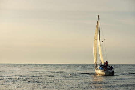 White sloop rigged yacht sailing in the Baltic sea at sunset. Clear sky after the storm, soft sunlight. Transportation, travel, cruise, sport, recreation, leisure activity, lifestyle, familyの写真素材