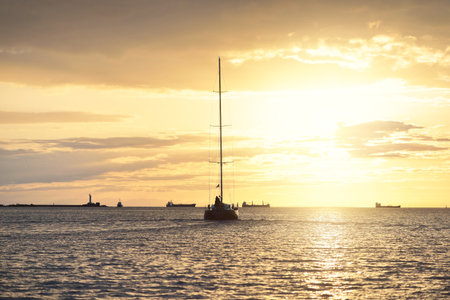 Sloop rigged yacht sailing in the Baltic sea. Sunset. Dramatic sky after the storm, golden sunlight....
