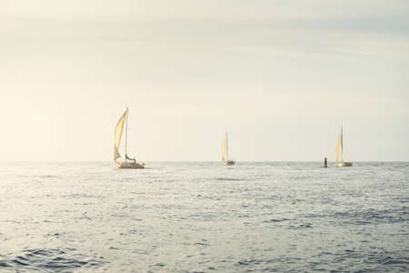 Sloop rigged yacht sailing in the Baltic sea. Sunset. Dramatic sky after the storm, soft sunlight. Transportation, travel, cruise, yachts racing, sport, recreation, leisure activity, lifestyle, familyの写真素材