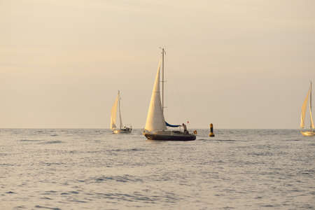 Sloop rigged yacht sailing in the Baltic sea. Sunset. Dramatic sky after the storm, soft sunlight. Transportation, travel, cruise, yachts racing, sport, recreation, leisure activity, lifestyle, familyの写真素材