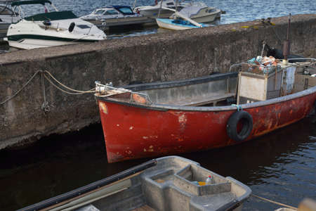Fishing boats and cutters moored to a pier in a yacht marina on a clear summer day. Private vessel for rent, transportation, recreation, vacations, leisure activity, sport, hobby, traditional craftの写真素材