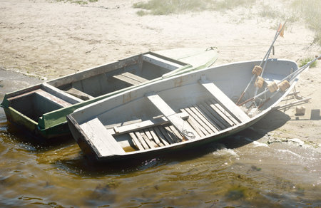 Old wooden fishing boats on the sandy Baltic sea shore on a clear day, close-up. Transportation, traditional craft, recreation concepts. Summer landscapeの写真素材