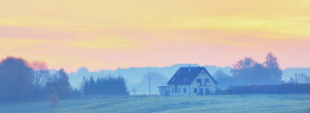 Epic sunrise above the lonely house, hills, field and forest. Colorful autumn landscape. Idyllic...