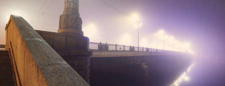 Illuminated empty Stone bridge in a fog at night. Lanterns close-up. Daugava river, Riga, Latvia. Concept image, neon colorsの写真素材