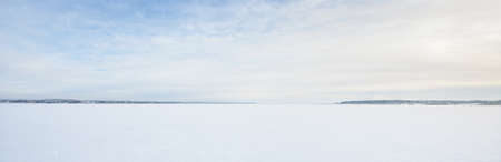 Frozen snow-covered lake under a clear blue sky with cirrus clouds. Fresh snow texture. Arctic, Lapland. Global warming, winter sport and fishing, environmental conservation themeの写真素材