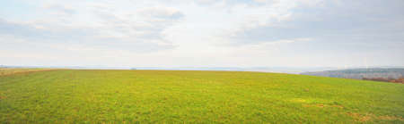 Picturesque panoramic scenery of the plowed agricultural field. Dramatic sky with glowing clouds,...