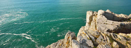 Aerial view of the rocky shore of Pointe de Pen-Hir, cliffs close-up. Cloudy blue sky, azure water, stormy waves. Dramatic cloudscape. Crozon peninsula, Brittany, Franceの写真素材