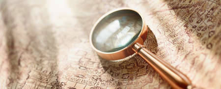 Retro copper colored magnifying glass and old white nautical chart close-up. Vintage still life. Sailing accessories. Travel, navigation concepts, collecting, graphic resource, hand lens, opticsの写真素材